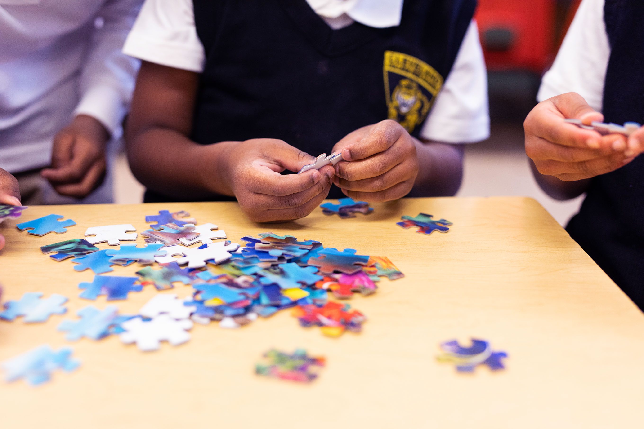 Students doing a puzzle at a desk.