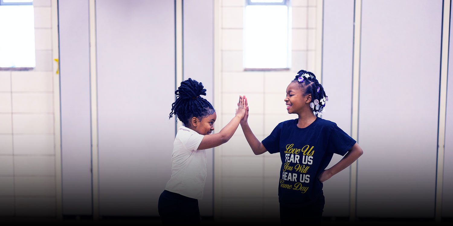 Smiling students giving each other a high five.
